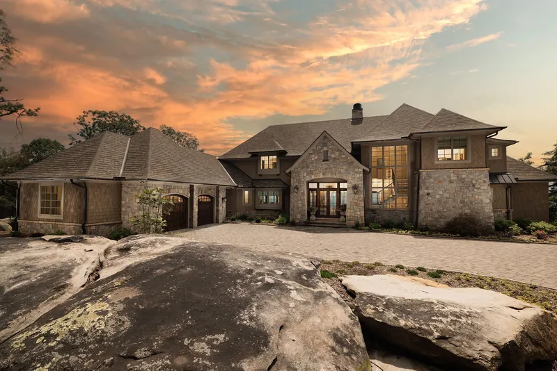 Highview Haven, a stone custom home set above natural rock beneath a sunset sky