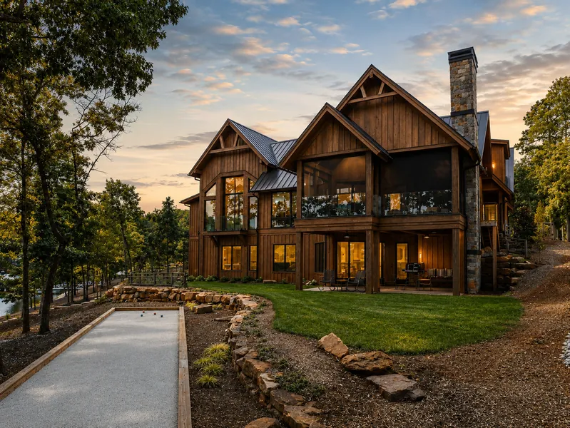 Wood-clad custom home with large windows, stone details and a sloping driveway