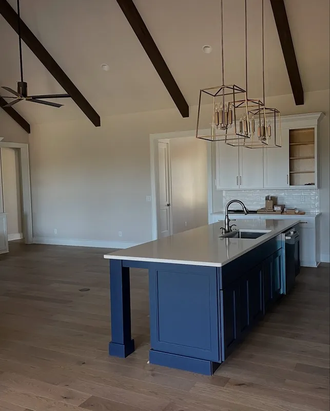 Custom kitchen with a blue island, light cabinets and exposed ceiling beams